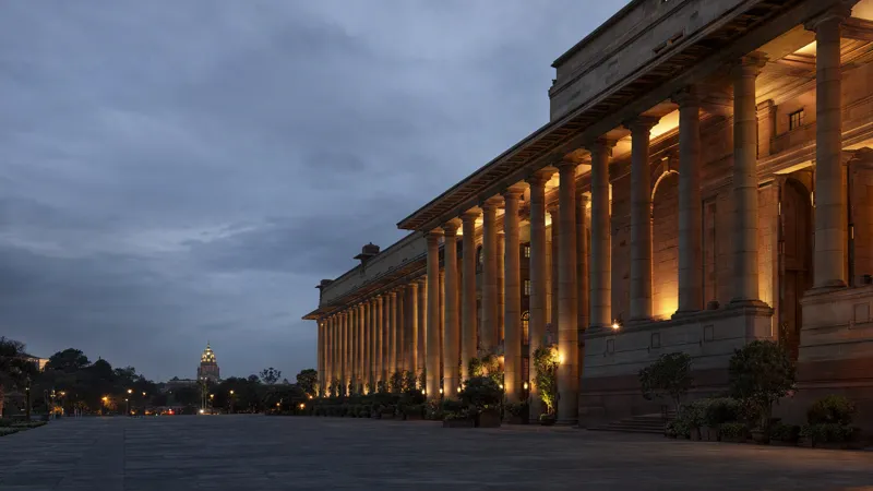 A state government administrative building at dusk, warm light between the columns of its stone colonnade